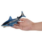 A realistic toy shark party favor being held in a hand